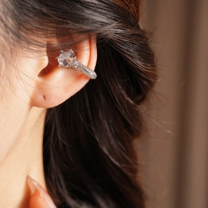 Gros plan d'une manchette d'oreille argentée avec zircon rond et cristaux pavés