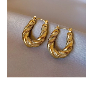 Close-up of golden U-shaped twisted metal earrings with horizontal spiral texture