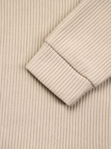 Detailed macro view of the beige ribbed knit texture and elastic cuffs on the sleeve