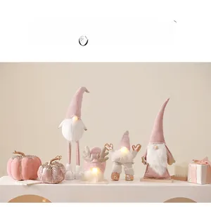 Detail of pink Christmas gnome ornaments with warm lights on minimalist display stand