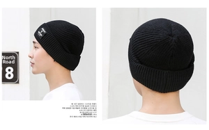 Detailed knit texture of a black winter beanie featuring a white MOMENT square woven label