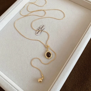 Macro detail of vintage tiger eye stone pendant on gold snake chain with small zircon accents