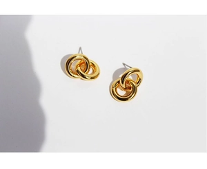 Macro shot of minimalist high-polish gold double-circle stud earrings on white background