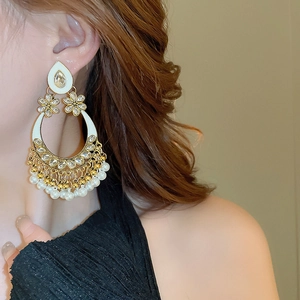 Close-up of ethnic style teardrop earrings with pearls and crystals on a model