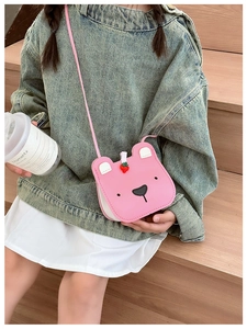 Close-up of pink bear-shaped crossbody bag with strawberry charm for girls