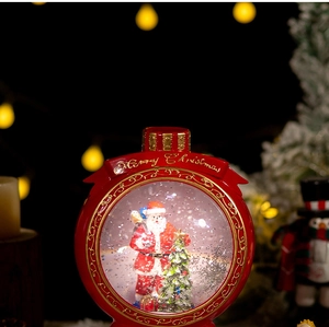 Macro detail of Christmas snow globe with Santa Claus, Xmas tree and Merry Christmas text