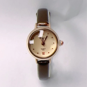 Close-up of a rose gold quartz watch with a beige dial and dark brown leather strap