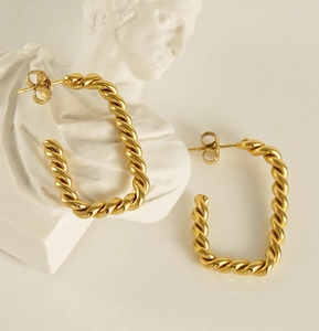 Detailed view of gold twisted rope hoop earrings on an artistic white bust display