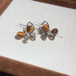 Détail de boucles d'oreilles papillon avec œil de tigre et zircons sur carte cadeau