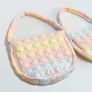 Detailed macro view of pink gradient quilted puffer bag with golden zipper and rhombus pattern