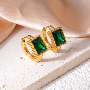 Detail view of gold star hoop earrings with emerald-cut green zircon and beaded texture