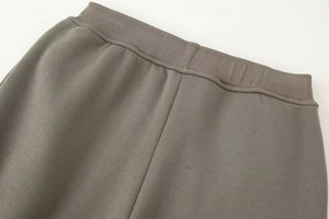 Detail of ribbed elastic waistband on grey knitted cotton joggers with neat stitching