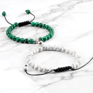 Detail of magnetic couple bracelets with malachite and turquoise beads on marble surface
