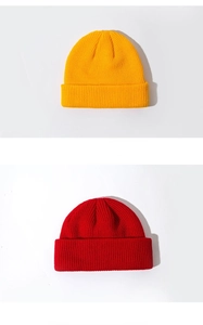 Detailed knit texture of classic yellow and red beanie hats on a white background