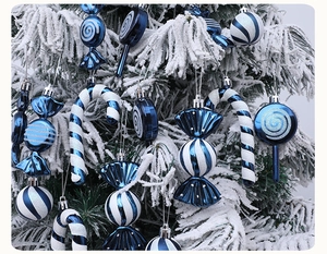 Close-up of blue and white glitter candy ornaments hanging on a snowy Christmas tree branch