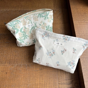 Blumige Kosmetiktaschen aus Baumwolle mit Reißverschluss auf einem Vintage-Holztisch