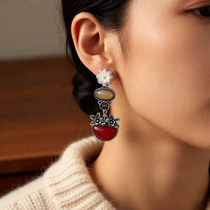 Close-up of vintage flower earrings with amber stone and red crescent drop on model
