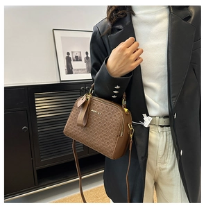 Detail of brown monogram shell bag featuring JIAONIKA gold logo and leather texture