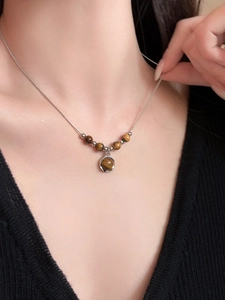 Detail view of tiger eye stone pendant necklace on model with vintage snake chain