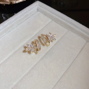 Détail macro de boucles d'oreilles fleurs dorées avec zircons pavés et design créole