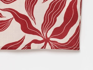 Detailed close-up of linen blend fabric with red leaf print and neat hem stitching