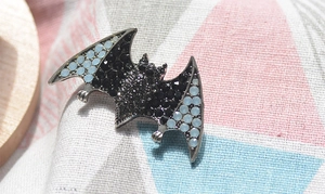 Macro shot of bat brooch with black and light blue rhinestones on plaid fabric