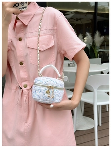 Close-up of white sequin round handbag with metal chain strap and pearl zipper detail