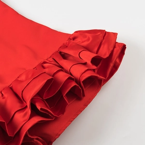 Close-up of red ruffled layers on a glossy satin fabric showing premium garment craftsmanship