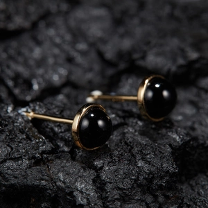 Macro shot of minimalist gold S925 silver stud earrings with round black jasper stones