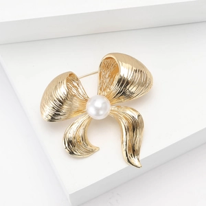 Elegant gold bow brooch with a central pearl on a minimalist geometric background