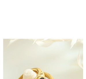 Detail of gold-plated jewelry with a white pearl and black gemstone accent