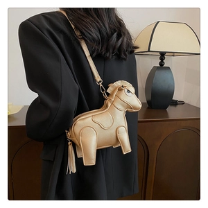 Golden horse-shaped crossbody bag with tassels shown on a model in a black blazer