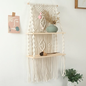 Detail of a two-tier handmade woven macrame wall shelf with beige cotton ropes and wood