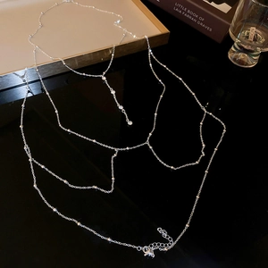 Détail d'une élégante chaîne de corps argentée multicouche avec perles et breloques cristal