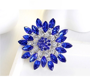 Detail of a floral brooch featuring navy marquise stones and radiant blue crystals
