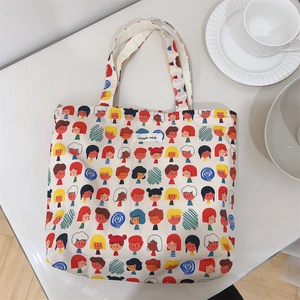 Flat lay of floral canvas tote bag with cartoon portraits near a coffee cup and saucer