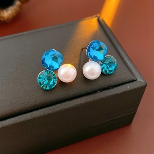 Macro view of triangle crystal stud earrings with blue gems and white pearls