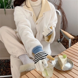 Close-up of striped knit gloves with touchscreen tips in a cozy outdoor cafe setting