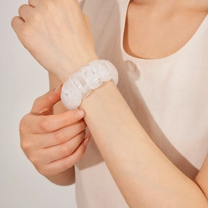 Close-up of chunky white marble resin links on a geometric elastic bracelet worn by model