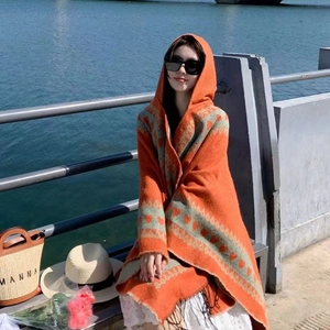 Détail d'un poncho à capuche orange avec motifs de cœur et longues franges de style