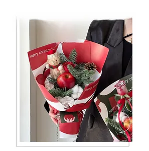 Macro detail of Christmas bouquet with teddy bear, red apple and festive wrapping paper