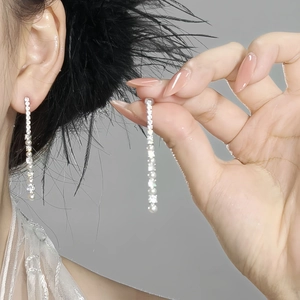 Macro detail of silver drop earrings with shimmering crystals and a single pearl drop