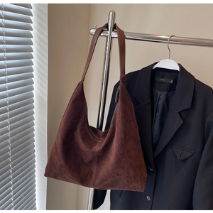 Detail view of large dark brown suede hobo bag hanging with elegant metal zipper closure