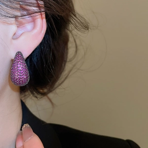 Macro shot of silver needle teardrop earrings with micro-paved purple zircon stones