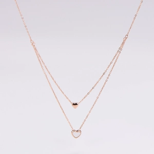 Detail of rose gold double-layered necklace with solid and white heart-shaped pendants