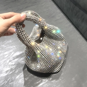 Detailed close-up of sparkling silver rhinestone bucket bag with knotted handle design