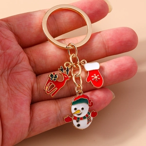 Detailed view of a gold Christmas keychain with red reindeer, glove, and snowman charms