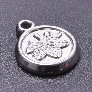 Macro shot of silver stainless steel round pendant featuring an embossed snowflake design