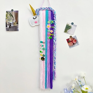 Détail d'un organisateur de barrettes licorne en feutre avec des glands en fil coloré