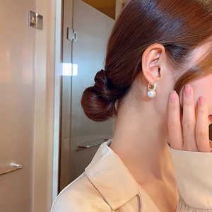 Elegant gold U-shaped earrings with large round pearls and pavé diamonds on model